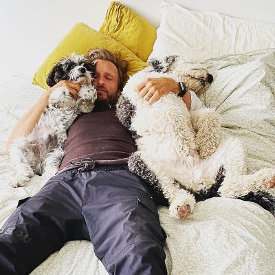 He is sleeping with his two dogs.